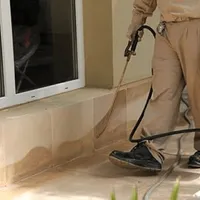 General pest control technician spraying exterior perimeter around a home in Providence, RI