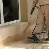 General pest control technician spraying exterior perimeter around a home in Providence, RI